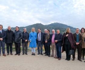 Grupo de pessoas de pé com pequenos montes atrás de paisagem natural